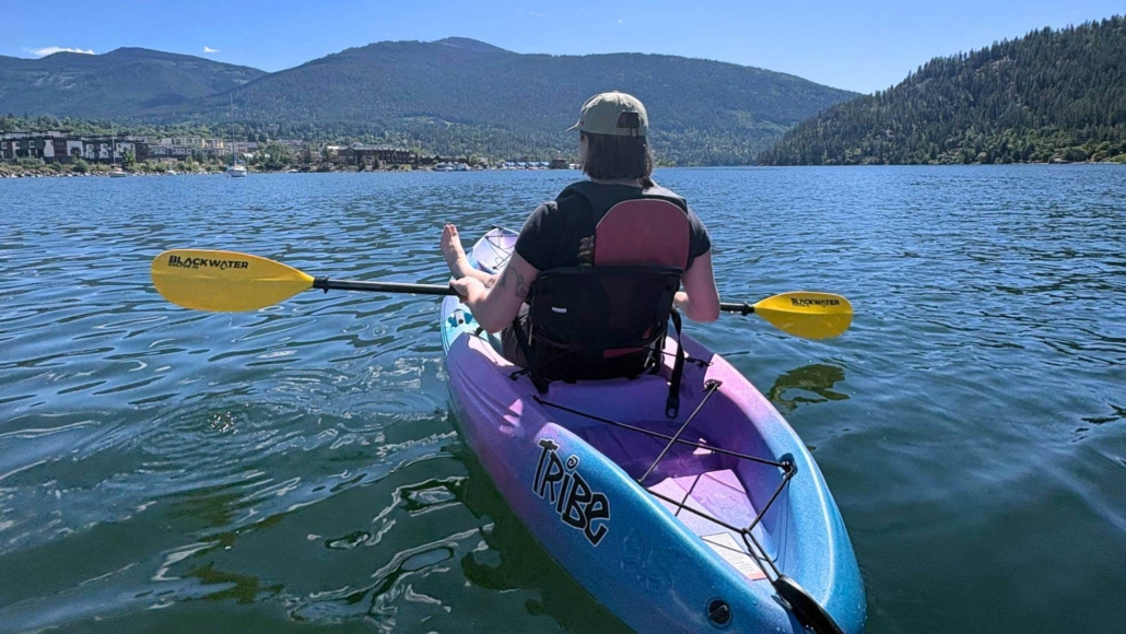 Woman kayaking on a lake surrounded by mountains