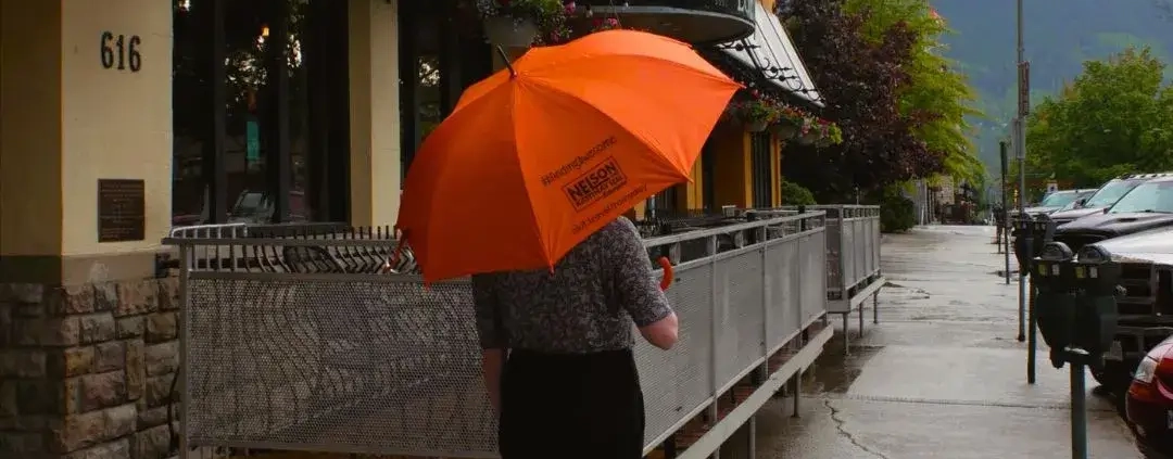 person standing outside of the adventure hotel holding an umbrella